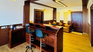 A modern kitchen with wooden accents, a central island with bar stools, and a dining area with a sofa and cushions. - Kanavu Valley View Resort (Coonoor)