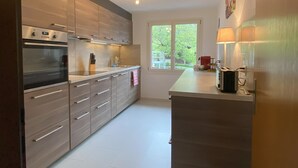 Een moderne keuken met roestvrijstalen apparatuur, houten kastjes en een groot raam voor natuurlijk licht.