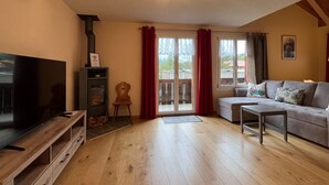 Een woonkamer met een televisie, een open haard, een bank en een schuifpui.