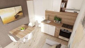 Une cuisine moderne avec des armoires blanches, un plan de travail en bois et un four encastré. On y trouve un coin repas avec une table et des chaises, ainsi qu’un canapé dans un coin.