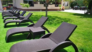 Une rangée de chaises longues disposées sur une pelouse bien entretenue, avec un bâtiment en arrière-plan.