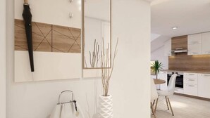 Una cocina moderna con armarios blancos, encimera de madera y un comedor con una silla blanca.