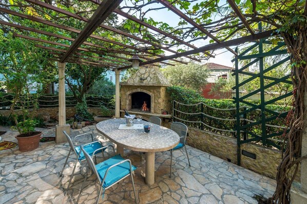 An outdoor patio with a stone table and chairs, a stone oven, and a pergola structure. - Green Terrace Apartment I (Dubrovnik)