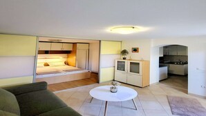 Un espacio habitable compacto con cama, kitchenette y un pequeño comedor.
