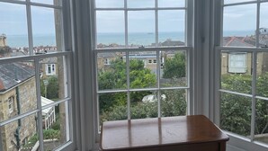 A bay window with a view of the sea and surrounding buildings. - Elm Cottage, first floor apartment with stunning coastal views (Seaview)
