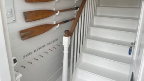A staircase with white railings and wooden planks hanging on the wall labeled "SHOES - FLIP FLOPS - SANID SHOES". - Elm Cottage, first floor apartment with stunning coastal views (Seaview)