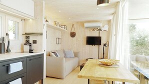 A modern kitchen with a dining area, a sofa, and a TV.