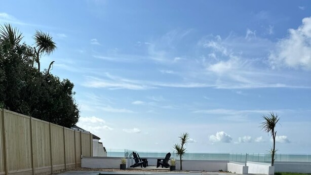Une piscine avec des chaises longues et vue sur l’océan.