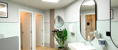 Un baño moderno con dos lavamanos, un espejo grande y una planta en maceta.
