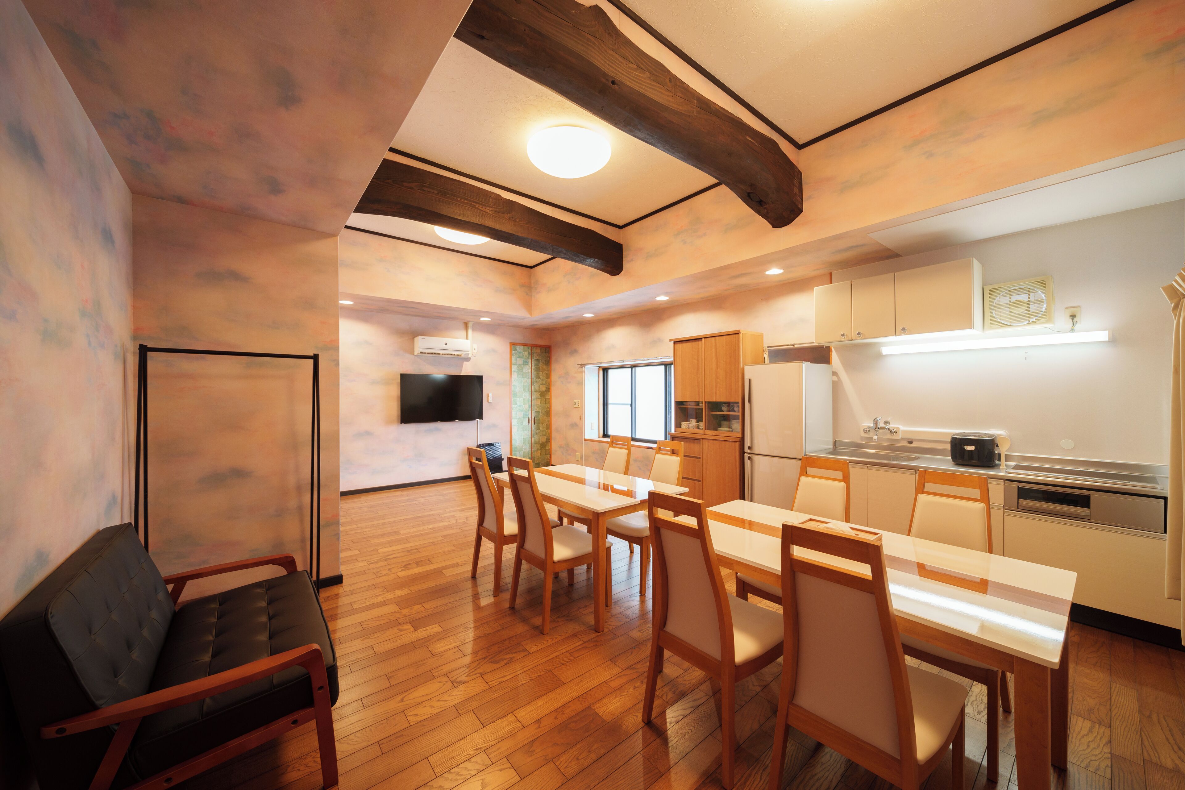 A spacious kitchen with wooden flooring, a dining table with chairs, and a built-in oven.