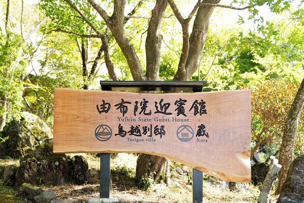 A wooden sign with text in Chinese and English, indicating a guest house named Yufuin State Guest House, located at Torigoe villa in Kuria. - Yufuin Geihinkan Kura (Yufu)