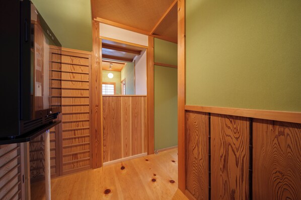 A hallway with wooden paneling and a black appliance on the left. - Yufuin Geihinkan Kura (Yufu)