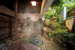 A traditional Japanese onsen with a stone hot spring surrounded by rocks and greenery. - Yufuin Geihinkan Kura (Yufu)