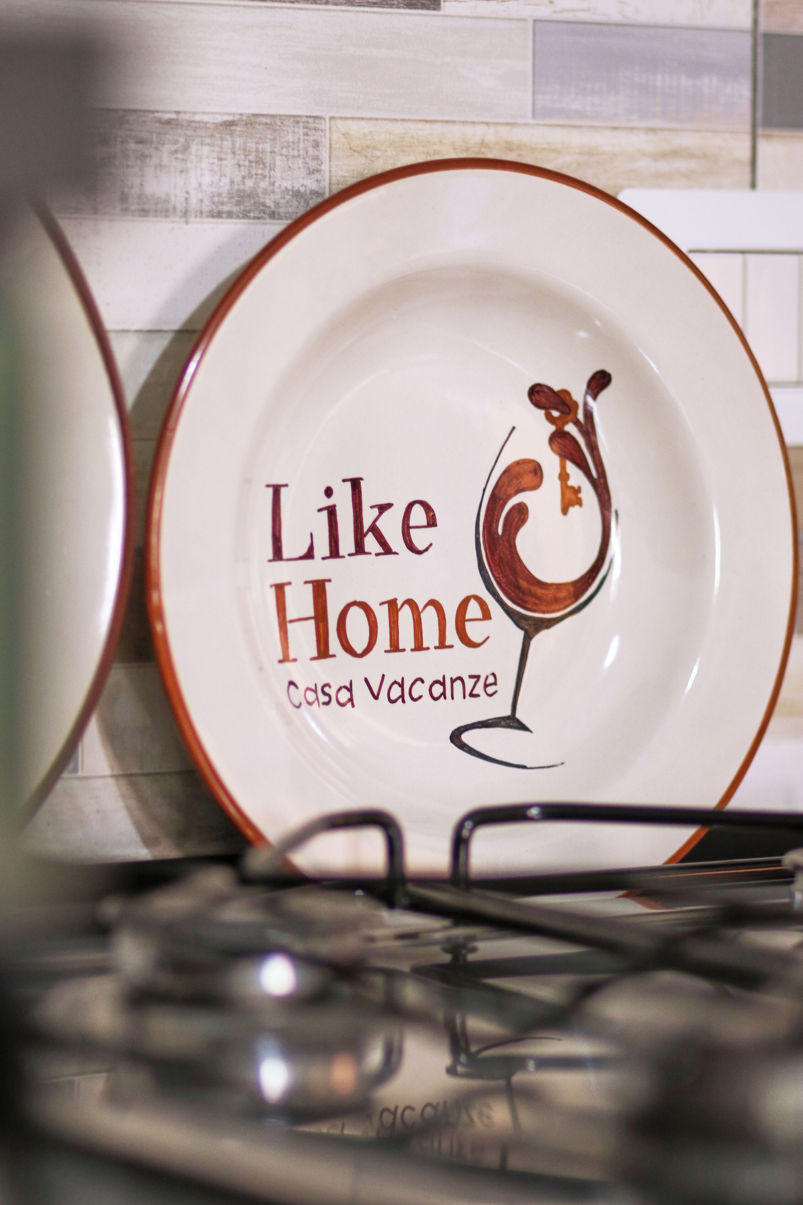 A plate with the text "Like Home Casa Vacanze" and a wine glass illustration.
