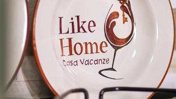 A plate with the text "Like Home Casa Vacanze" and a wine glass illustration.