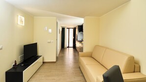 En moderne stue med et fladskærms-tv, en beige sofa og et sort tv-møbel.