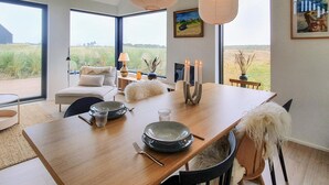 Ein Essbereich mit einem Holztisch, gedeckt für vier Personen, einer Couch und Blick ins Freie.