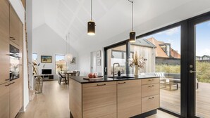 Eine moderne Küche mit Holzausstattung, einer Mittelinsel und Pendelleuchten.