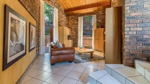 Un amplio salón con pared de ladrillo, un sofá de cuero y una mesa de centro de madera.