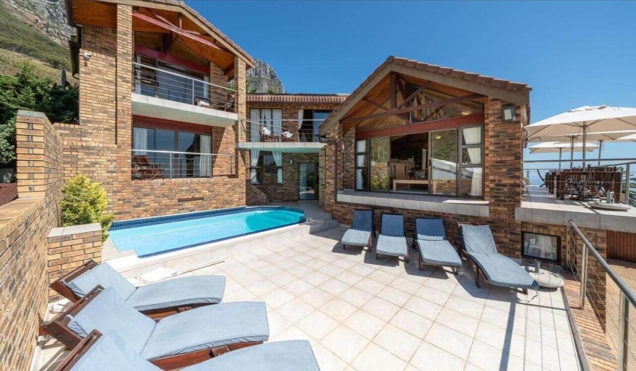 Eine moderne Villa mit Swimmingpool, Sitzgelegenheit im Freien und einem Balkon mit Blick auf die Landschaft.