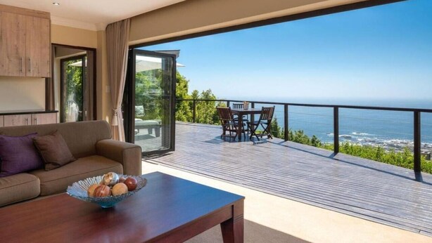 Una sala de estar moderna con un ventanal grande, una mesa de madera y un sofá.