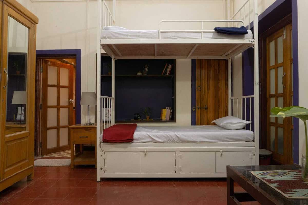 A bunk bed room with a desk, a chair, and a small table with a plant.