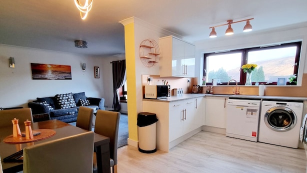 Eine moderne Küche mit Mikrowelle, Toaster und Spüle. Es gibt einen Essbereich mit Tisch und Stühlen.