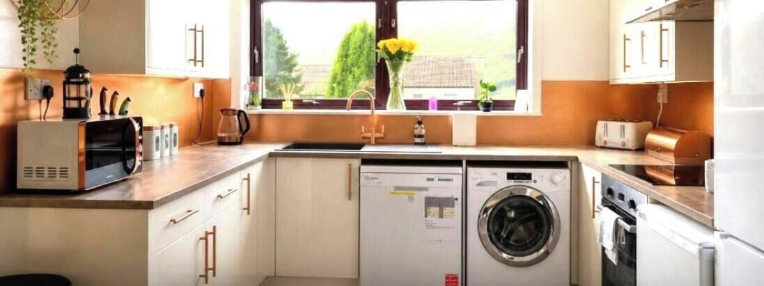 Een kleine keuken met een wasmachine, een broodrooster en een koffiezetapparaat.