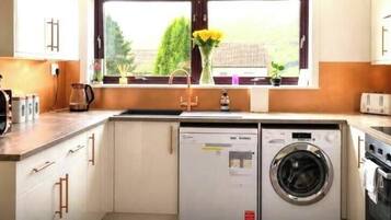 Een kleine keuken met een wasmachine, een broodrooster en een koffiezetapparaat.