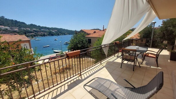 A balcony with a view of boats on a lake, a table with chairs, and a railing. - Apartment Dominik - Two Bedroom Apartment with Terrace and Sea View (Smokvica)