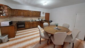 A compact kitchen with wooden cabinets, a microwave, and a dining table with chairs. - Apartment Dominik - Two Bedroom Apartment with Terrace and Sea View (Smokvica)