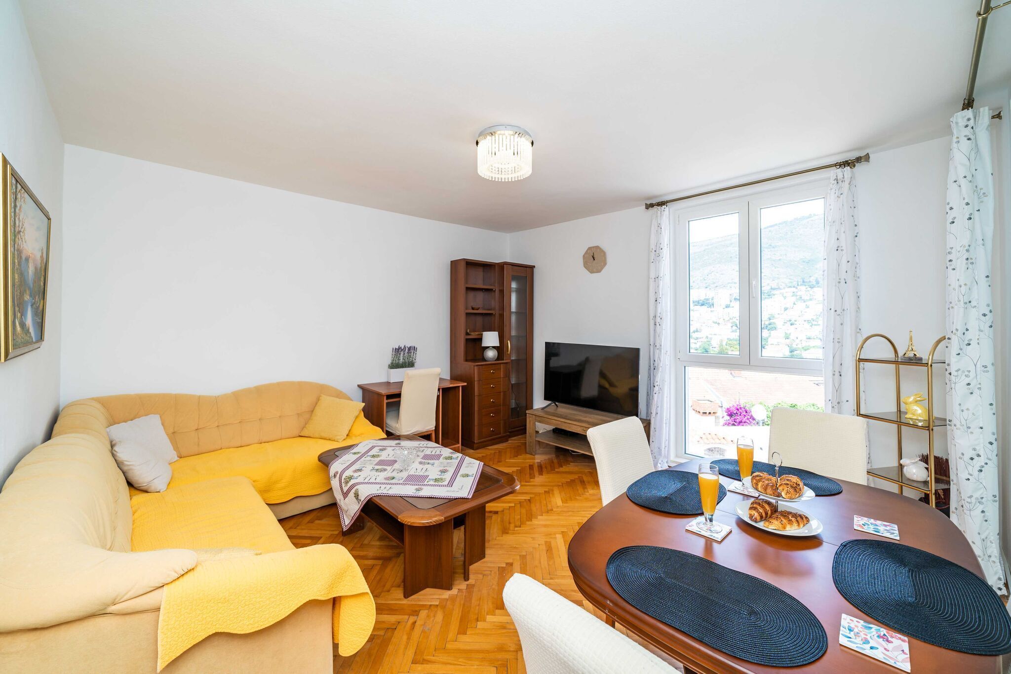 Un salon confortable avec un canapé, une table basse, un téléviseur et un coin repas où la table est mise pour le petit-déjeuner.