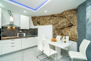 Een moderne keuken met witte kasten, een magnetron en een eethoek met een tafel en stoelen.