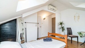 A bedroom with a wooden bed, a ceiling fan, a potted plant, and a dreamcatcher on the wall.