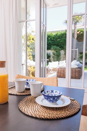 Enjoy a peaceful breakfast for two in a serene room with a view of lush greenery and outdoor seating.