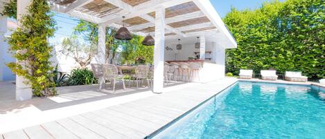 A poolside area with a covered seating area, a bar, and a pool.