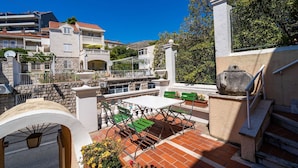 A terrace with a table and chairs, a stone wall, and a view of buildings in the background. - Rooms Nina - Double room with Sea View - 2 (Dubrovnik)