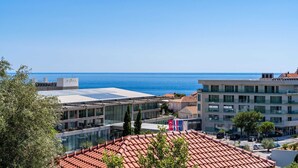 A coastal cityscape with modern buildings, a clear blue sky, and the sea in the background. - Rooms Nina - Double room with Sea View - 2 (Dubrovnik)