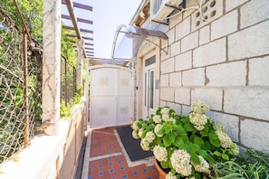 Pathway leads to a building with a stone facade and decorative metal gate.