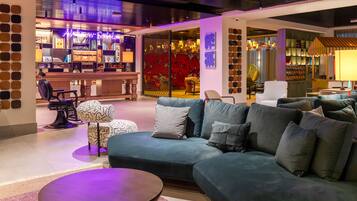 Relax in a stylish lobby with plush sofas, a coffee table, and a bar area.