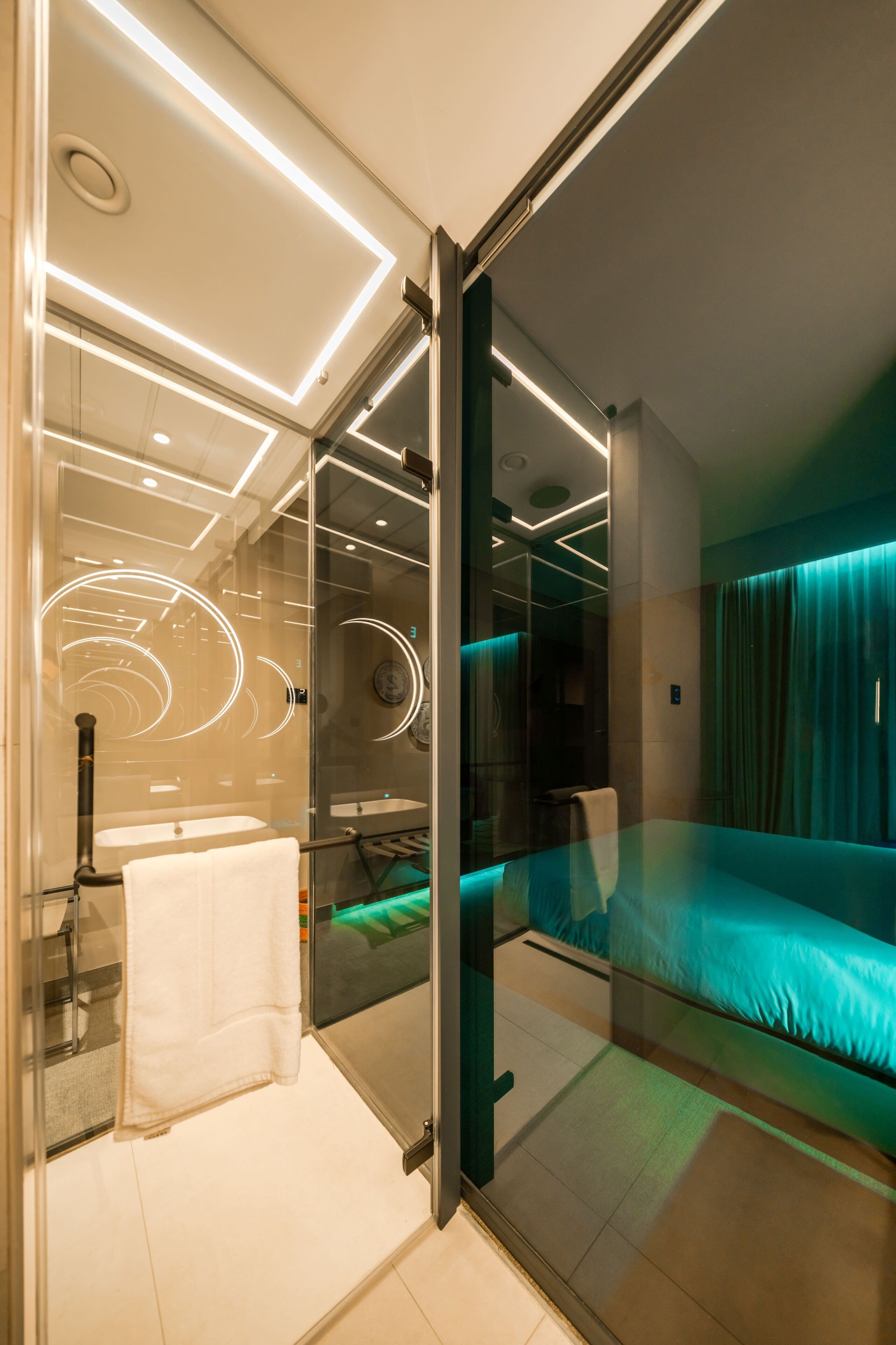 A modern bathroom with a glass partition, a white towel, and a visible clock.