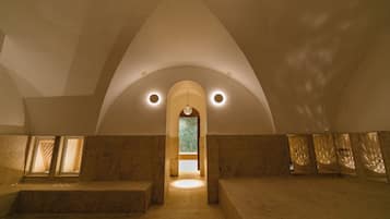 A spacious interior with a high arched ceiling, a central doorway, and a patterned wall at the far end.