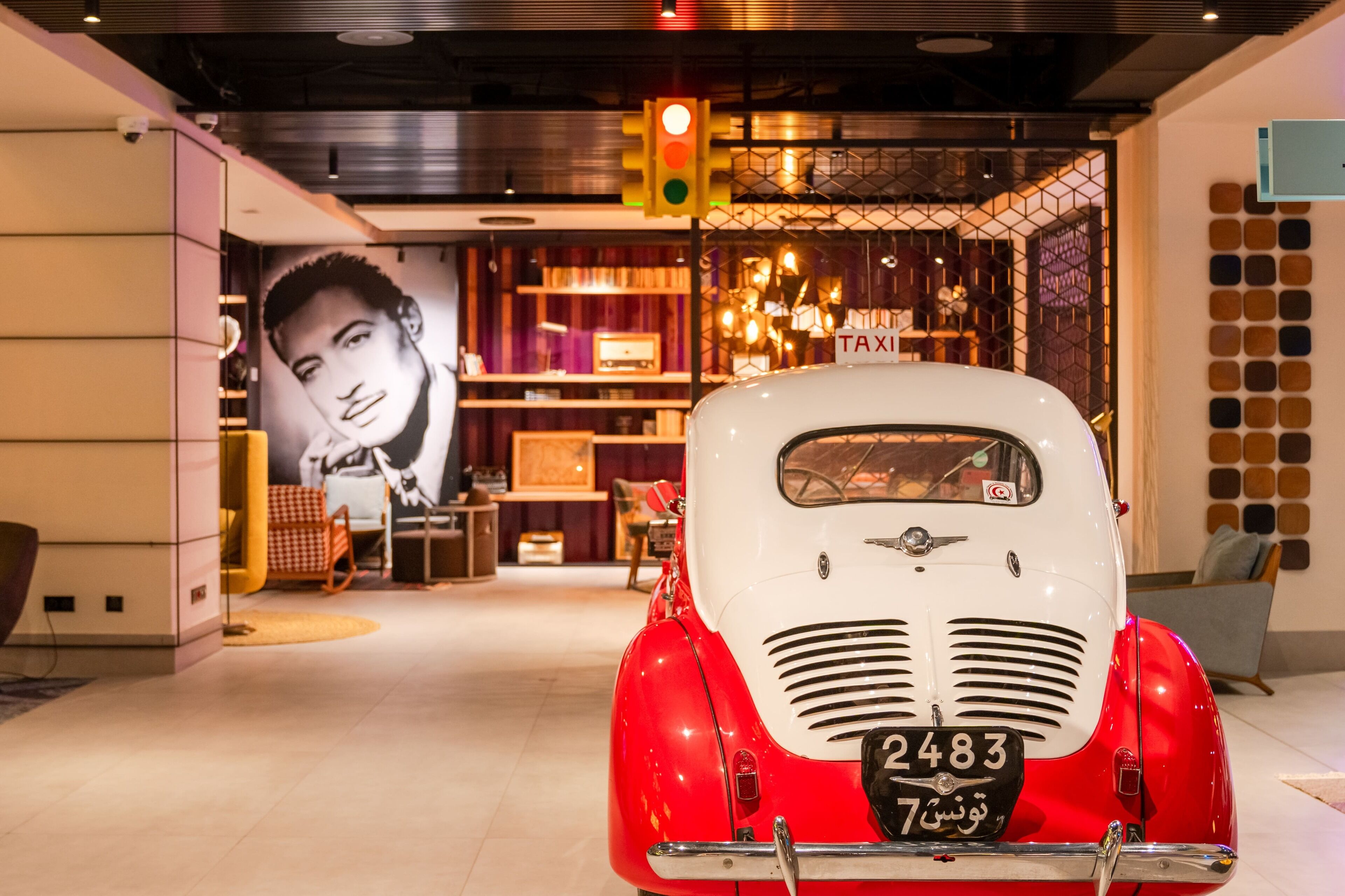 A vintage car in a modern interior with a traffic light and a 'TAXI' sign.
