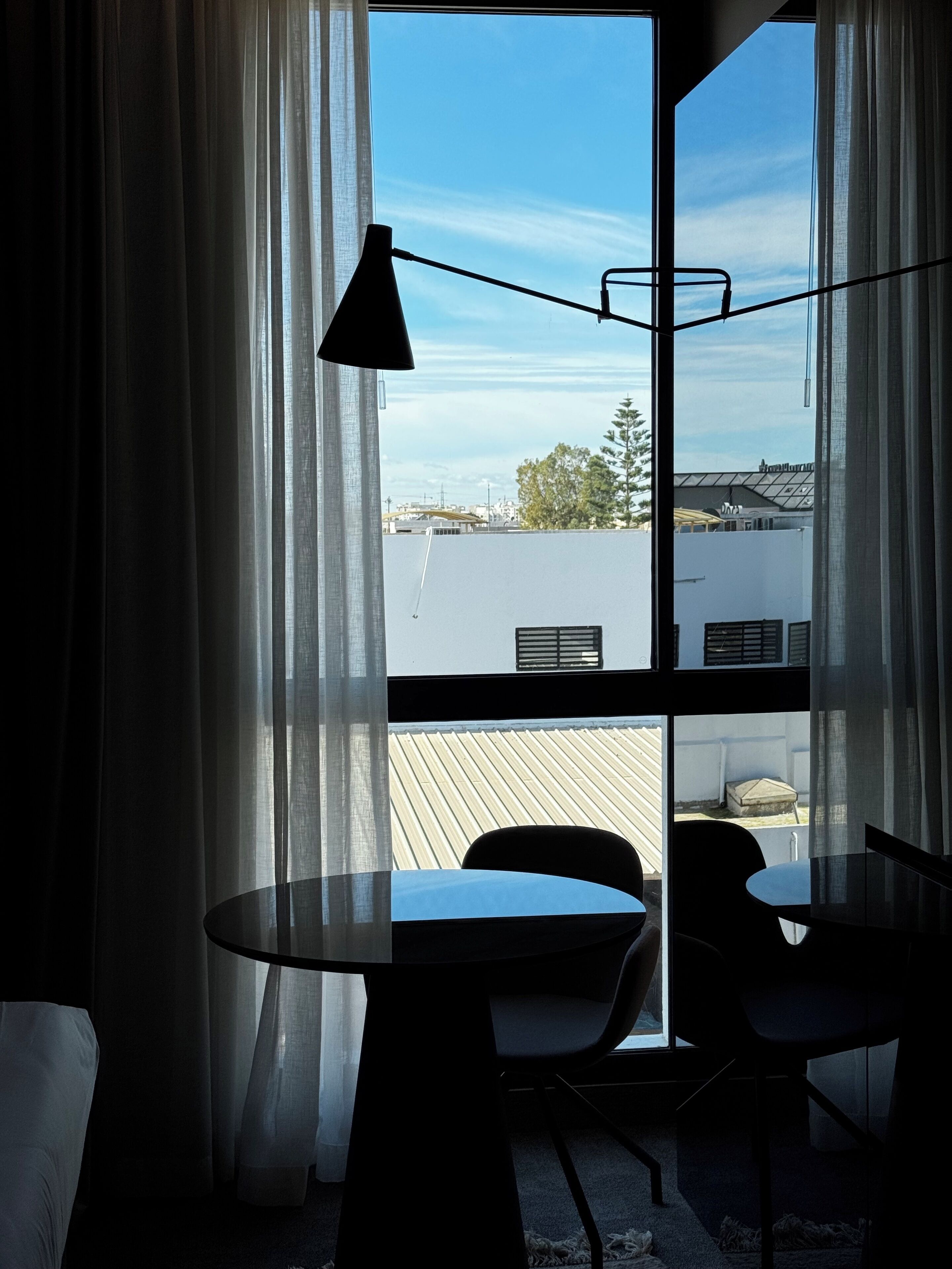 Ein Zimmer mit großem Fenster, einem Tisch und zwei Stühlen.