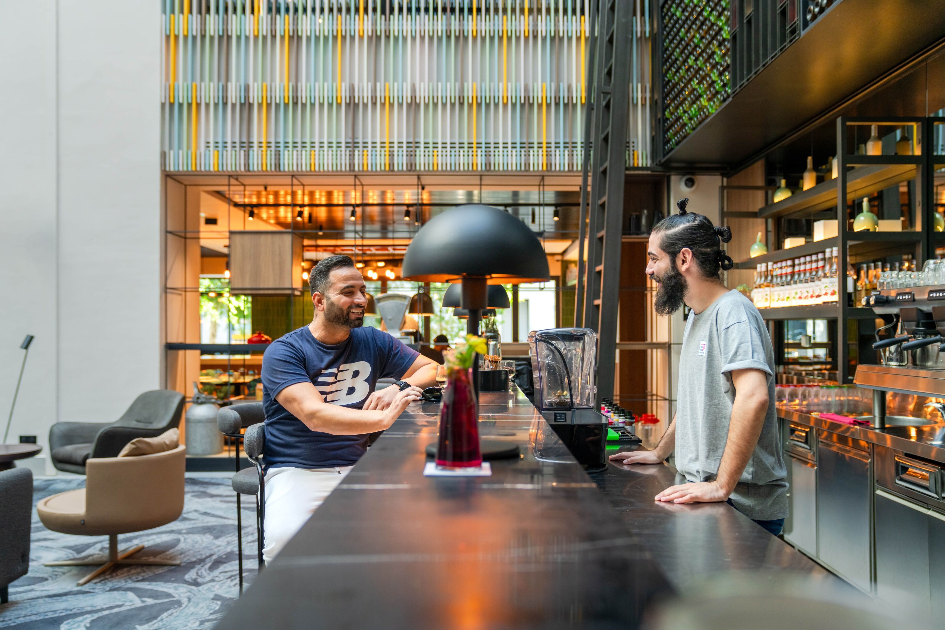 Un espace bar moderne avec un comptoir, des tabourets de bar et une grande lampe noire.