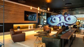 A modern lobby with a reception desk, seating area, and a large wall mural.
