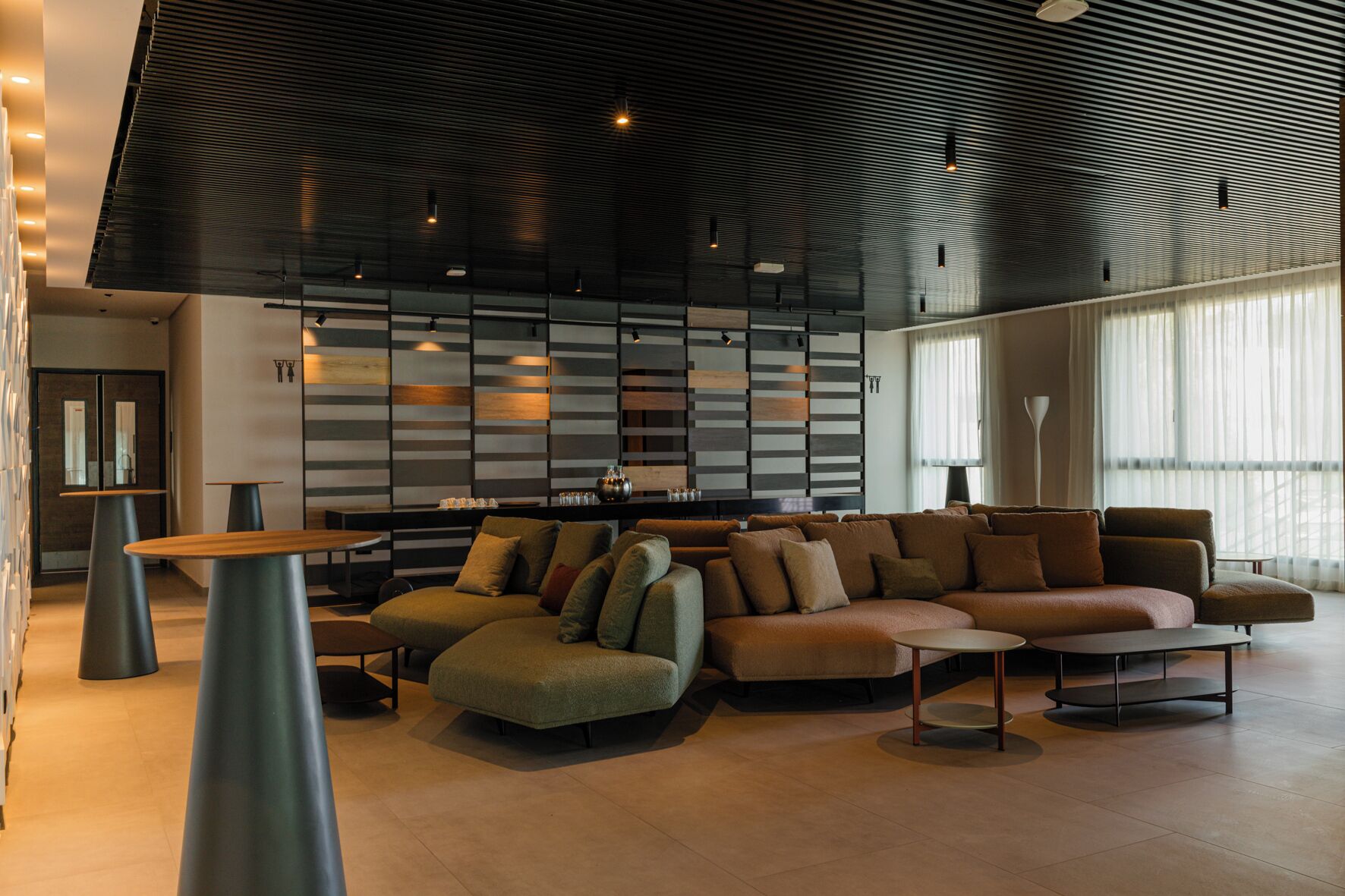 A modern interior with a sectional sofa, a round table, and a wall with horizontal lines.