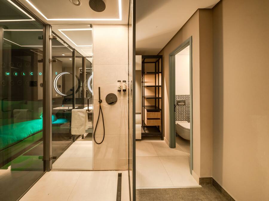 A modern hotel bathroom with a glass partition, a shower area, and a visible toilet.