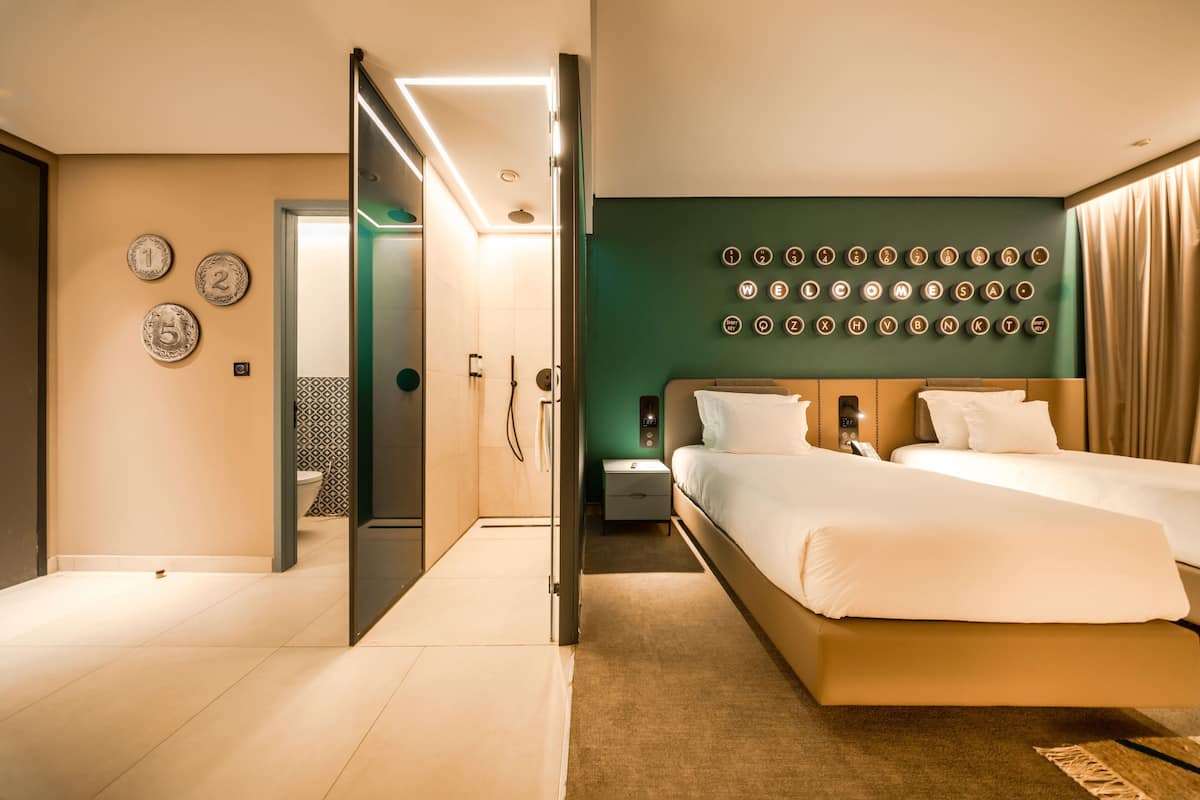 Ein modernes Hotelzimmer mit einem großen Bett, einem Nachttisch, einem Spiegel und einer Wand mit Runddekorationen.