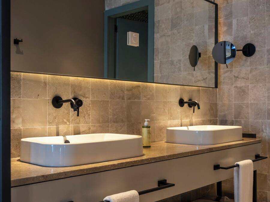 A modern bathroom with two sinks, a large mirror, and a towel rack.